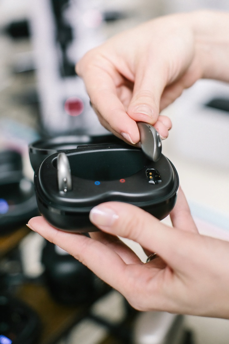 Hearing aids being placed in their charging case